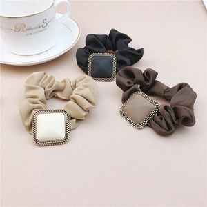 Detail of matte satin scrunchies with square bead-trimmed charms in neutral colors