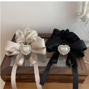 Detail of elegant oversized bow scrunchies with pearl heart and long mesh ribbons