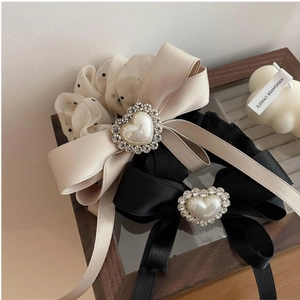 Detail of luxury pearl heart bow hair scrunchies in champagne and black satin fabric