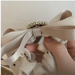 Detail of a French vintage champagne ribbon hair tie with pearl and polka dot chiffon