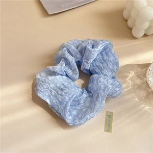 Détail du chouchou bleu clair à pois avec texture seersucker et design doux à volants