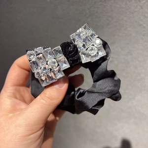 Vue détaillée du chouchou en satin noir orné de nœuds en strass scintillants