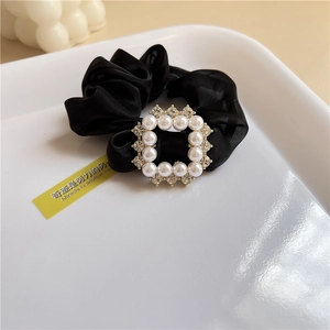 Detail of silk black scrunchie with a square faux pearl and rhinestone buckle