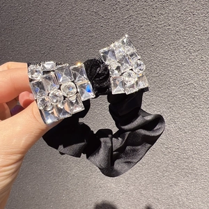 Détail d'un chouchou en satin noir avec un grand nœud en cristal orné de strass brillants
