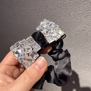 Vue détaillée d'un chouchou en satin noir de luxe orné d'un nœud étincelant en strass