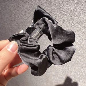 Détail d'un chouchou noir en satin avec nœud et étiquette Hand Made cousue main