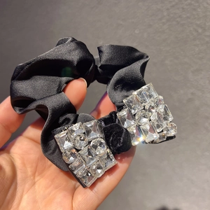 Détail d'un chouchou en satin noir de luxe avec des cristaux brillants rectangulaires