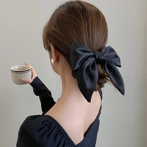 Elegant large black satin bow hair tie accessory for low bun hairstyle back view