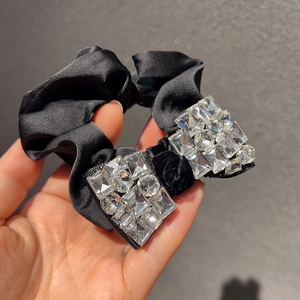 Gros plan d'un chouchou en satin noir avec nœud orné de strass brillants haute couture