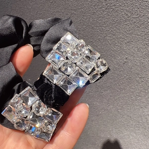 Vue macro des strass brillants et détails en velours sur un chouchou en satin noir
