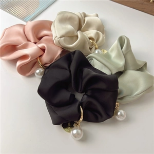Close-up of four satin scrunchies in pastel colors with pearl and heart charms