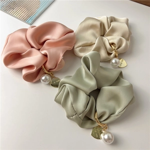 Close-up of pink and green satin scrunchies with faux pearl and heart-shaped charms