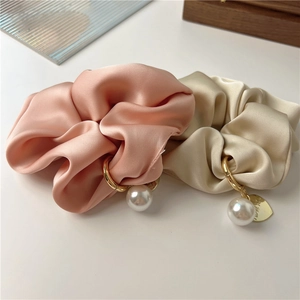 Close-up of satin scrunchies with faux pearls and heart tags in pink and gold