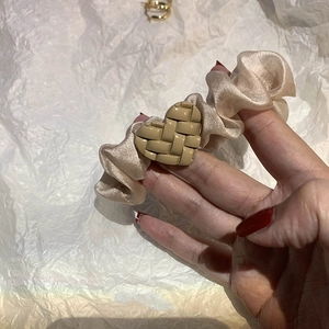 Close-up of champagne satin scrunchie with khaki woven heart detail in hand