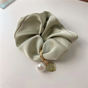 Detail of silk satin scrunchie featuring a white pearl and an engraved heart charm
