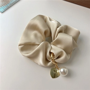 Detail of champagne gold satin scrunchie with heart pendant and pearl charm