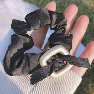 Nahaufnahme von elegantem schwarzem Satin-Haargummi mit matter goldener Schnalle und Band