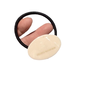 Minimalistisches handgefertigtes Haargummi mit beigem Anhänger und elastischem schwarzem Band
