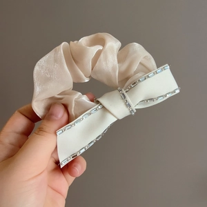 Sparkling rhinestone bow scrunchie in champagne satin fabric for elegant hairstyles