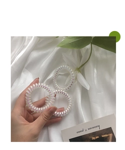 Drei schimmernde Spiral-Haargummis auf Seide mit Hand und Blumen-Dekoration