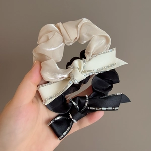 Close-up of champagne and black satin bow scrunchies featuring sparkling rhinestone edges