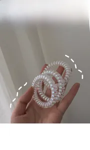 Drei Stück Laser-Perlmutt-Spiral-Haargummis mit holografischem Schimmer in der Hand