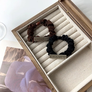Detail of scrunchies with square metal tags engraved with CHANCE and rhinestones