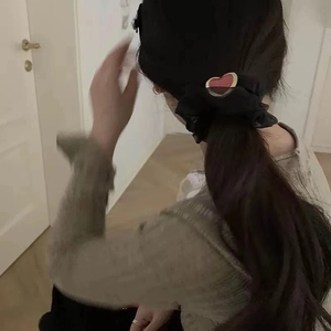 Detail eines schwarzen Herz-Haargummis an einem Pferdeschwanz für das Styling