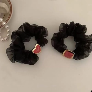 Detail von schwarzen Organza-Haargummis mit herz- und quadratförmigen Anhängern