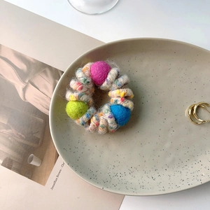 Close-up of colorful wool ball hair tie on decorative ceramic tray with art magazine