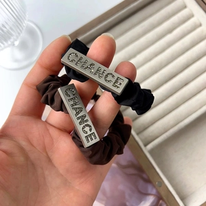 Detail of satin hair ties in black and brown featuring rhinestone CHANCE metal charms