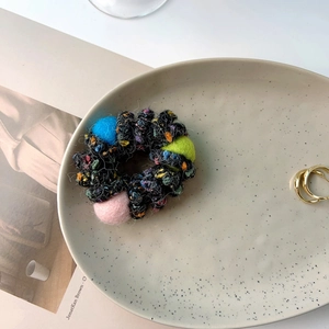 Winter plush telephone cord hair ring with colorful wool felt balls on ceramic tray