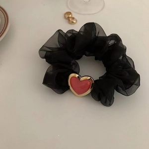 Detailansicht eines schwarzen Organza-Haargummis mit rotem Herzanhänger und Goldrand