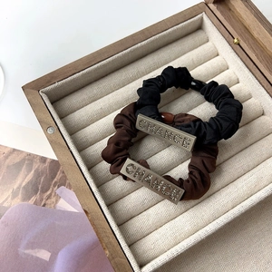 Detail of satin scrunchies with crystal CHANCE metal plate in a wooden box