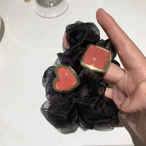 Detailansicht Haargummi aus schwarzem Organza mit herzförmigem Harzanhänger und Goldrand