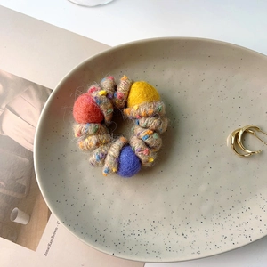 Detail of plush telephone wire hair tie with colorful wool felt balls on ceramic tray