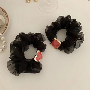 Detail von zwei schwarzen Organza-Haargummis mit roten Achat-Anhängern in Herzform