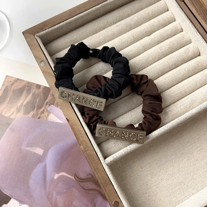 Detail of black and brown fabric hair ties with rhinestone CHANCE metal plate decoration
