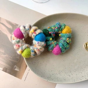 Colorful plush wool ball hair scrunchies on a ceramic plate with fashion background