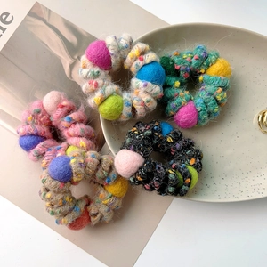 Detailed view of colorful knitted spiral hair ties with decorative soft plush pom-poms