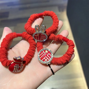 Macro detail of red plush hair ties featuring gold Fu character and sparkling rhinestones