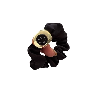 Elastic black satin scrunchie with a gold metal smiley face charm for stylish hair styling
