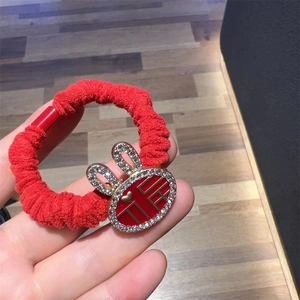 Detail of red scrunchie featuring a gold rabbit charm with rhinestones and Fu character