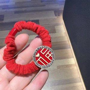 Detail of red knitted scrunchie with rhinestones and golden Chinese Double Happiness charm