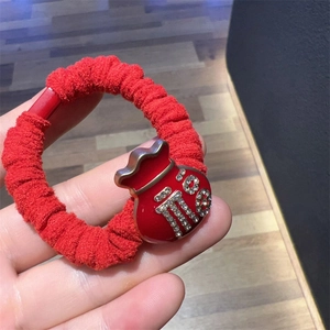 Close-up of a red lucky bag charm hair tie with sparkling rhinestone inlay details