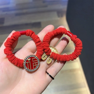 Macro detail of red plush scrunchies with Fu character and gold rabbit charms