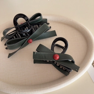 Vintage dark green leather bow hair claw clips with red beads set on a round tray