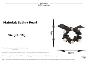 Detailansicht eines schwarzen Satin-Haargummis mit großen weißen Perlen und Metallanhänger