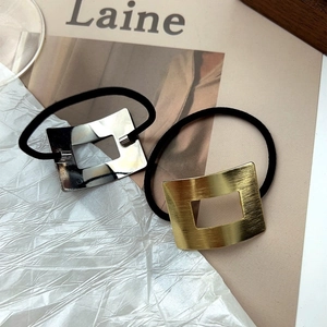 Dettaglio di fibbie in metallo spazzolato oro e argento su elastici per capelli chic