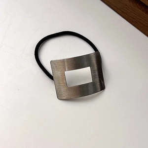 Dettaglio macro della fibbia in metallo satinato su elastico per capelli nero minimal